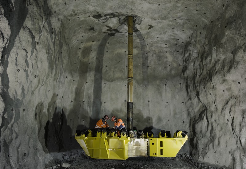 Två personer står på en gul borrkrona som monteras inför borrning.