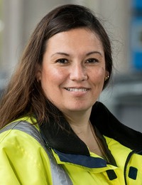 Victoria Valle har långt brunt hår och en gul arbetsjacka på sig.