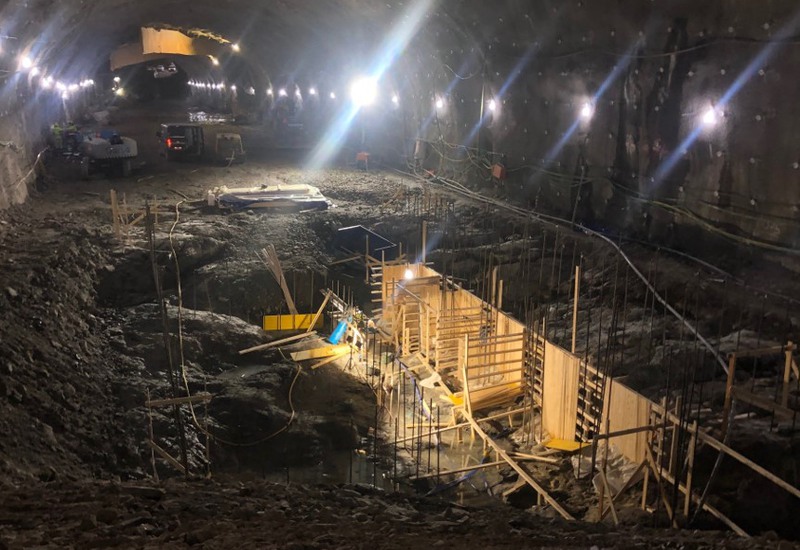 I en tunnel byggs grundfundamentet för Barkarby station upp. Det mörka bergrummet lyses upp av strålkastare.