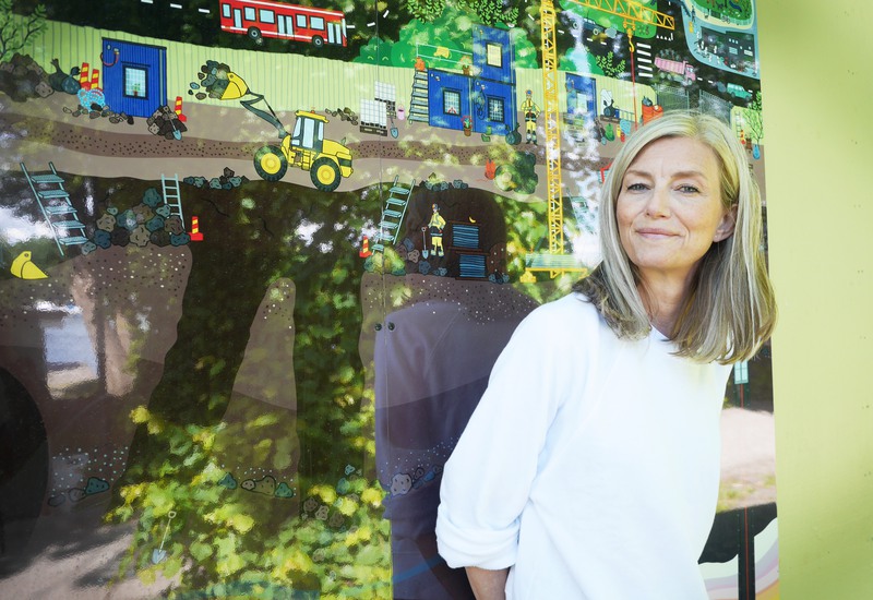 Kvinna står framför en skylt som illustrerar bygget av tunnelbanan