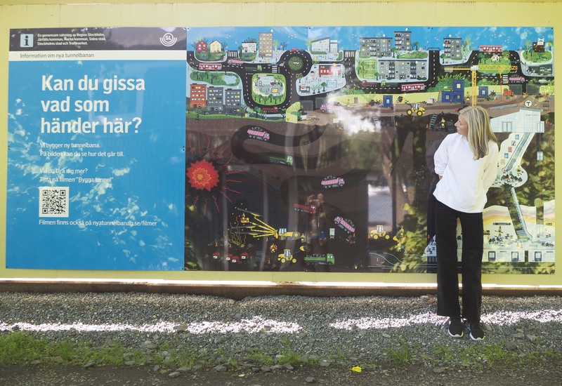 Bild på Sarah Sheppard stående framför illustrationen