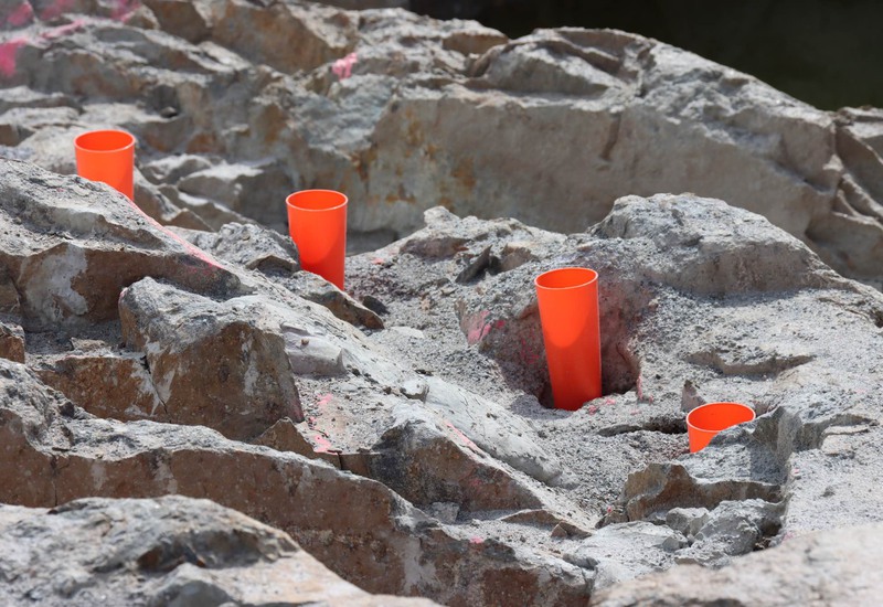 Brandgula konformade spränghattar i plast är nedstuckna i berget.