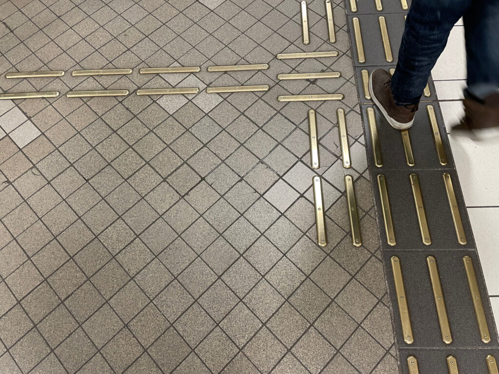 Mässingsfärgade metallskenor på en tunnelbaneplattform.