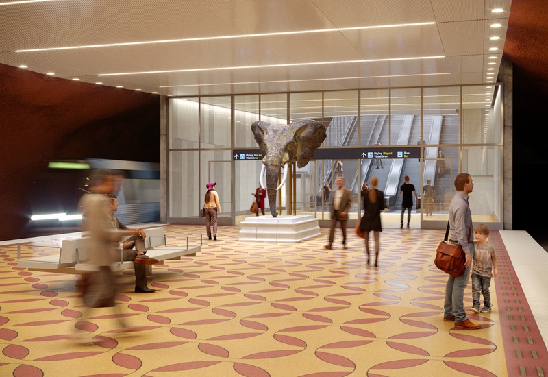 Visionsbild från Station Nacka visar plattformen. På plattformen syns människor vänta på tunnelbanan intill ett konstverk i form av en elefant.