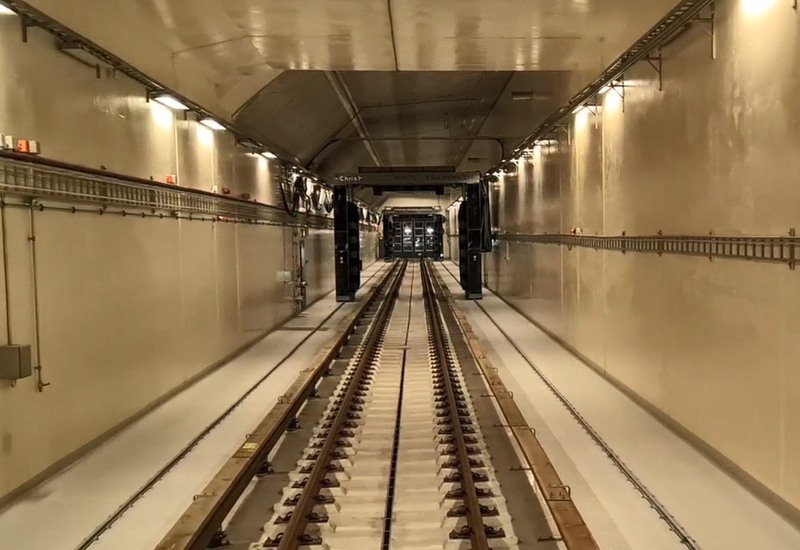 Ett långt vitt rum med tågspår i golvet. Längre bort syns en tvättmaskin på skenor.