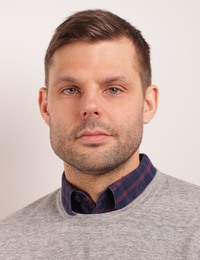 Porträttbild på Folke Köhlberg Roll. Brunt kort hår och skäggstubb.