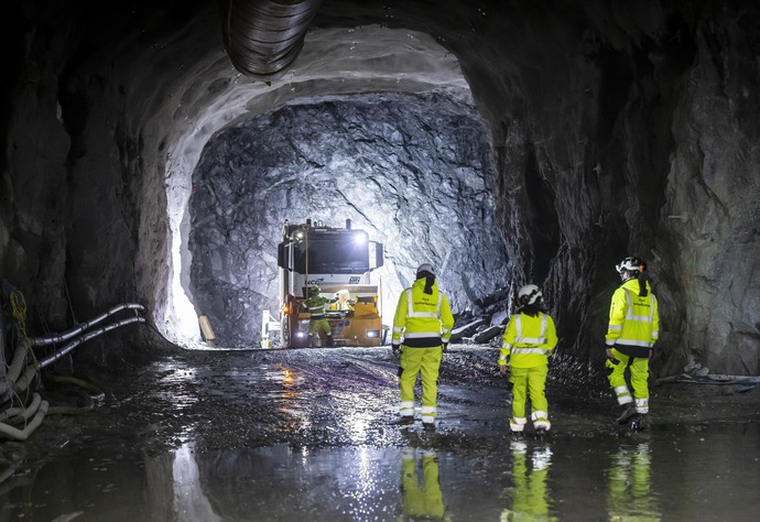 Tre personer i gula arbetskläder i en tunnel.