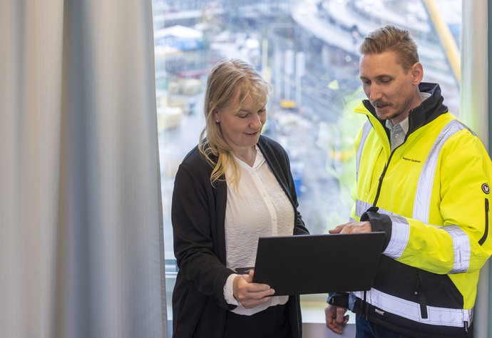 En kvinna och en man tittar på en bärbar dator och pratar,
