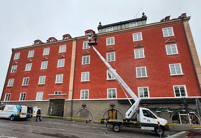 Husfasad med en kranlift framför.
