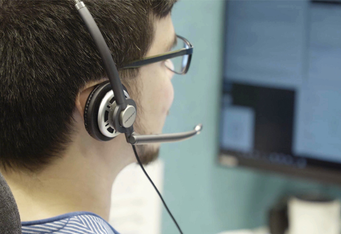Man med headset sitter framför datorskärm.