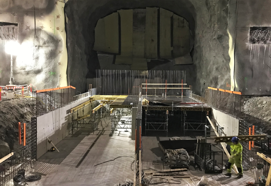 Bergrum där gjutning pågår. Armeringsjärn sticker upp och en arbetare i gula kläder jobbar.