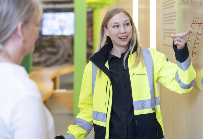 Person i gul byggjacka pekar på en karta.